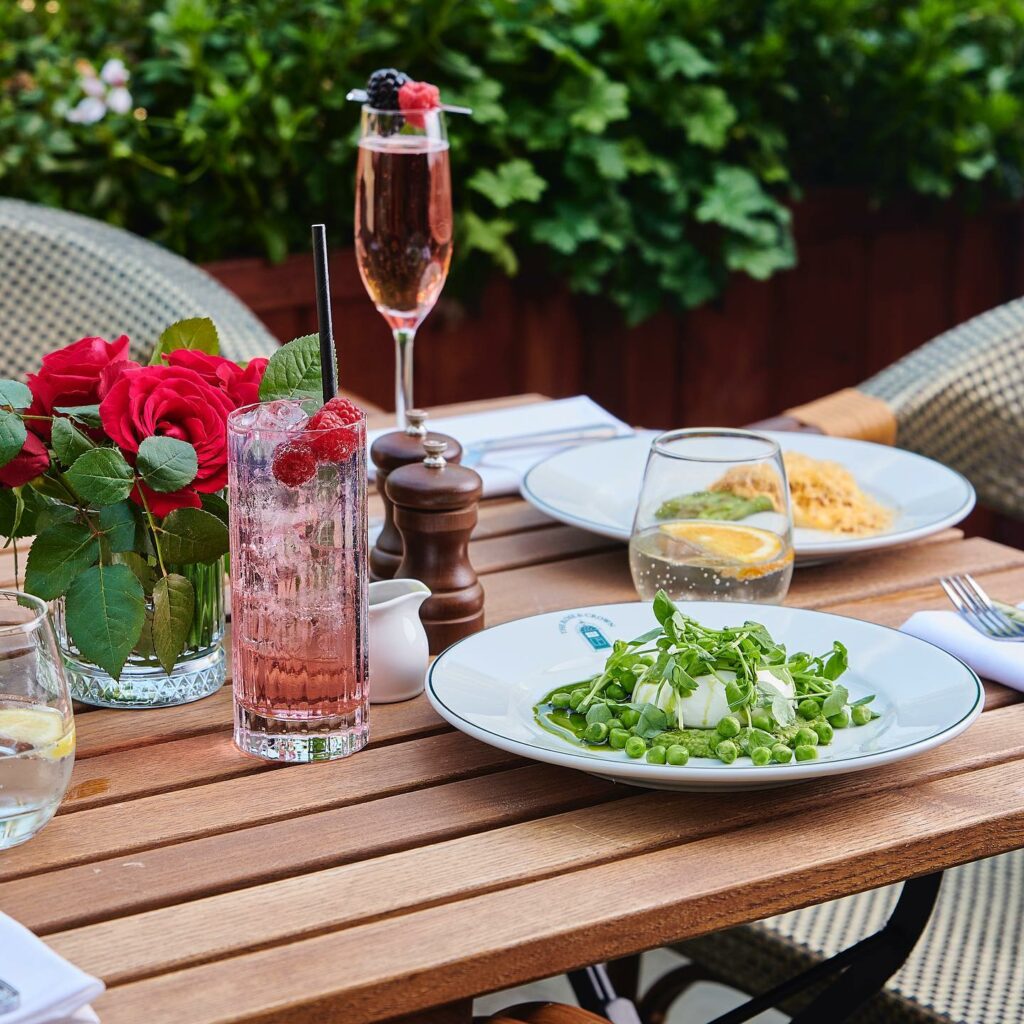 Showing a selection of drinks and dishes on an outside dining table, including cocktails 