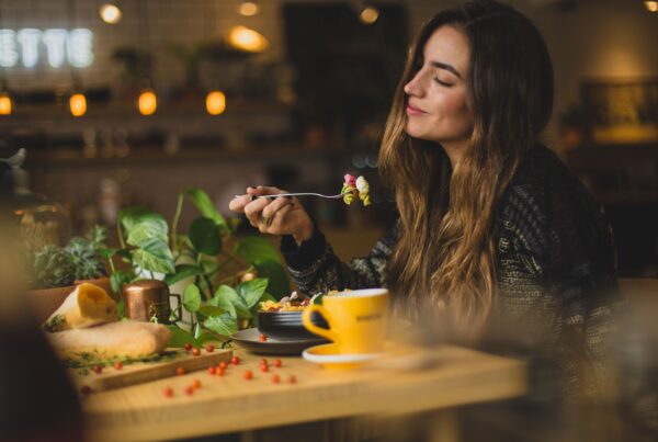 Female nutrition: Woman sat at a table eating and smiling