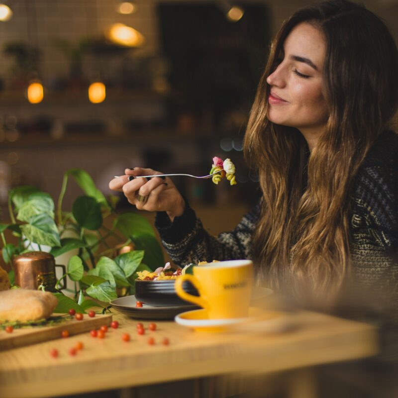 Female nutrition: Woman sat at a table eating and smiling