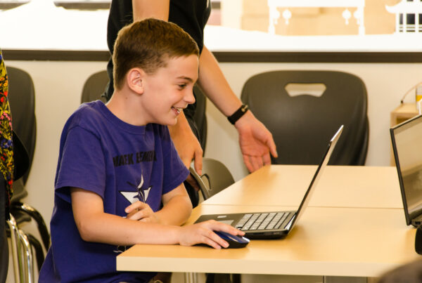 Boy smiling at laptop. AI has power to transform education.