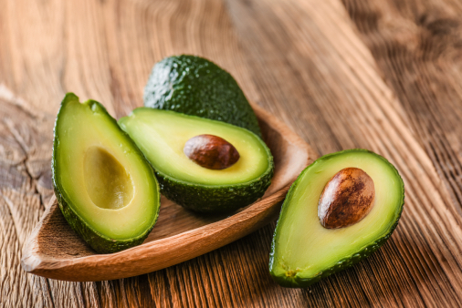 Avocado on old wooden table.Halfs on wooden bowl. Fruits healthy food darlingmagazineuk